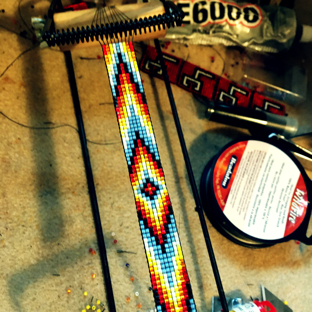 a beading loom with a finished blue, red, black, white, yellow beading design.